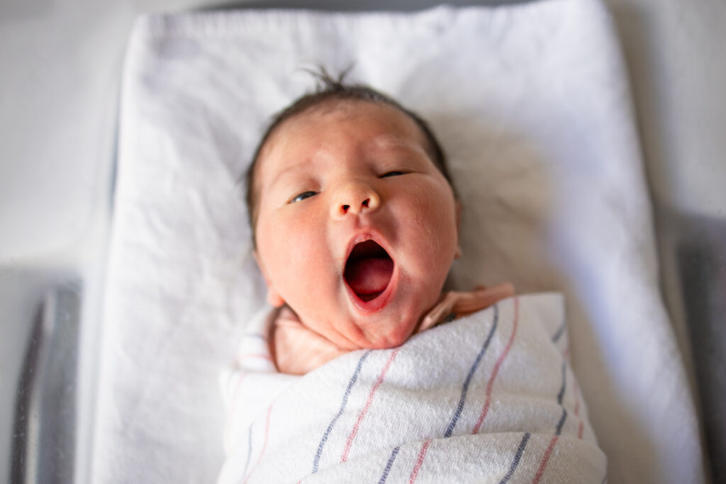 Newborn baby yawning in hospital bassinet during Fresh 48 photo session in Boston